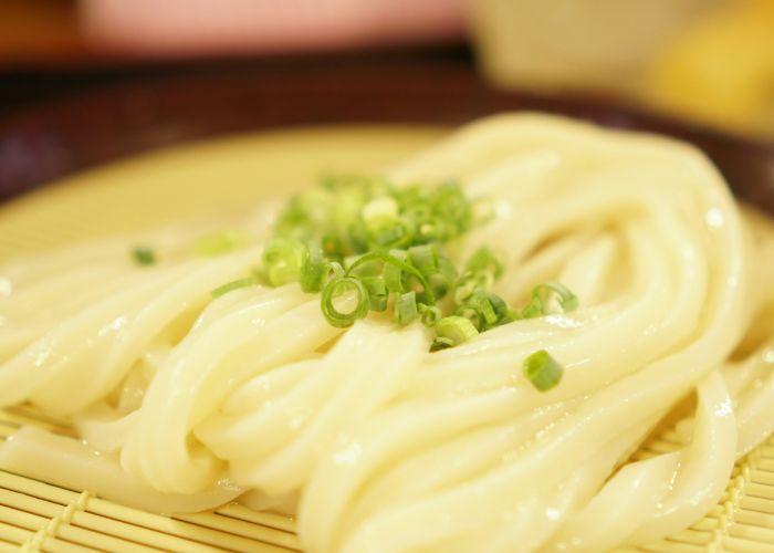 A serving of zaru soba on a bamboo tray, garnished with spring onion.